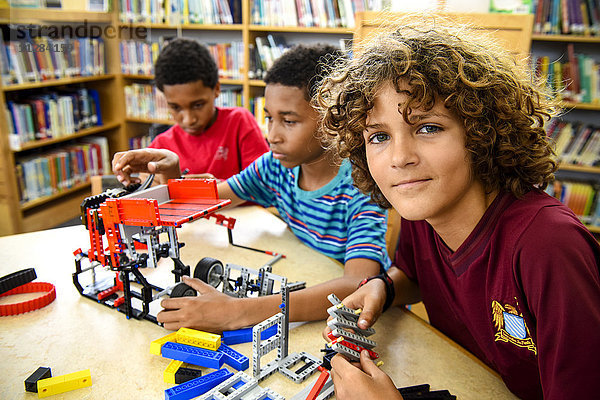 Jungen bauen in der Bibliothek Plastikblöcke zusammen