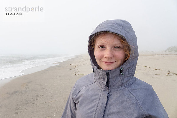 Porträt eines lächelnden kaukasischen Mädchens am kalten Strand