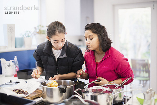 Mutter und Tochter schauen auf das kochende Essen hinunter