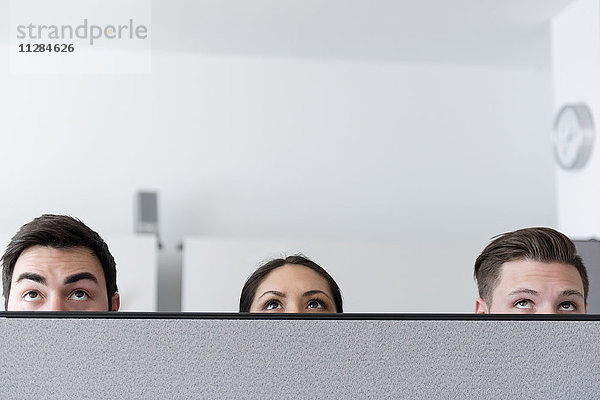 Augen von Geschäftsleuten  die über die Kabinenwand im Büro nach oben schauen