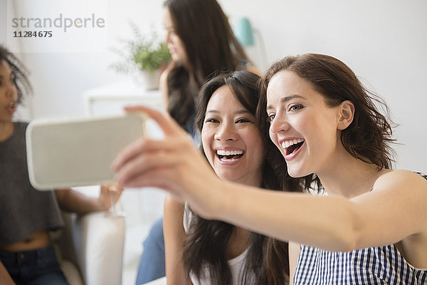 Lächelnde Frauen  die für ein Handy-Selfie auf einer Party posieren