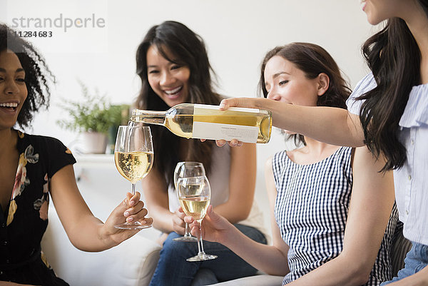 Frau schenkt eine Flasche Weißwein für Freunde ein