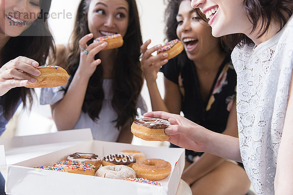 Lächelnde Frauen essen Donuts