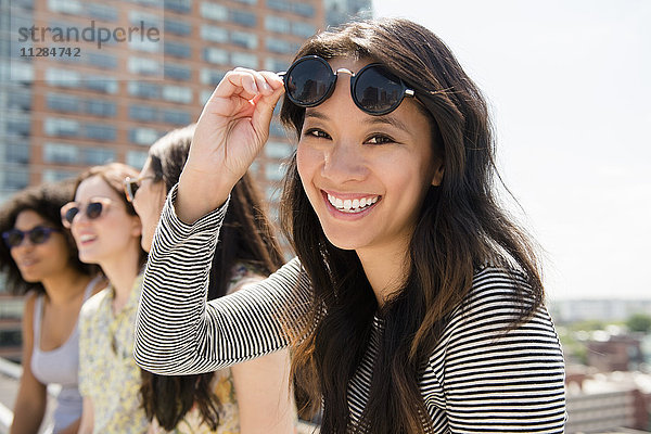 Lächelnde Frau hebt Sonnenbrille im Freien