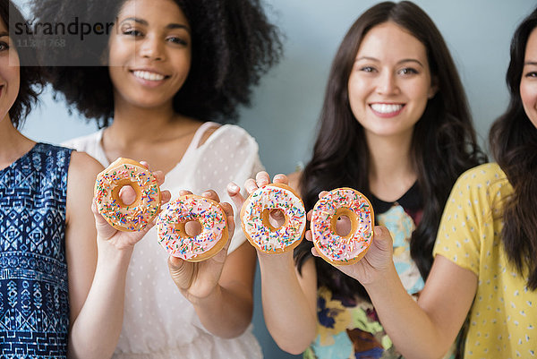 Porträt einer lächelnden Frau  die mit Donuts posiert