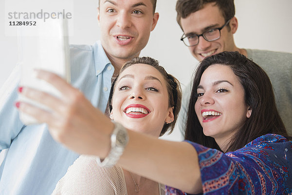 Lächelnde kaukasische Freunde posieren für ein Handy-Selfie