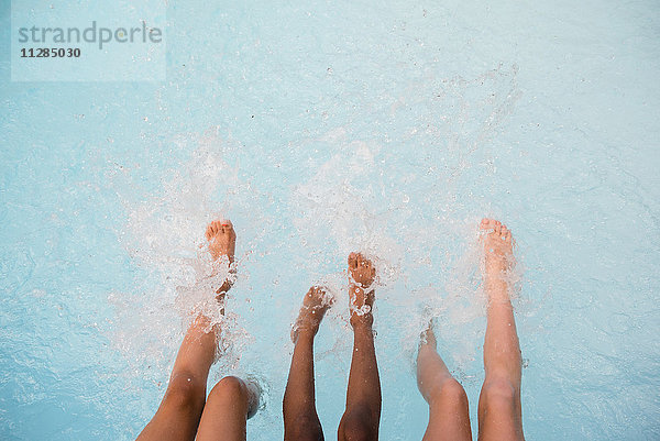 Beine von Mädchen spritzen Füße im Schwimmbad