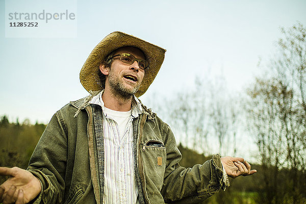 Kaukasischer Bauer mit Cowboyhut  der im Freien spricht und gestikuliert