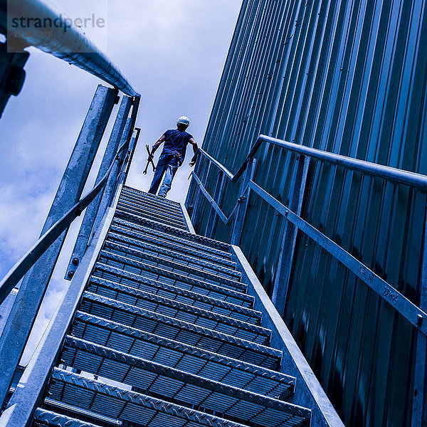 Kaukasischer Arbeiter trägt Werkzeuge auf einer Treppe