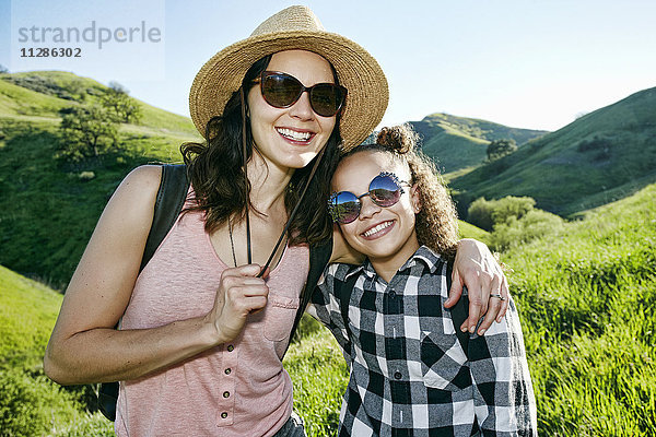 Lächelnde Mutter und Tochter mit Sonnenbrille auf einem Hügel
