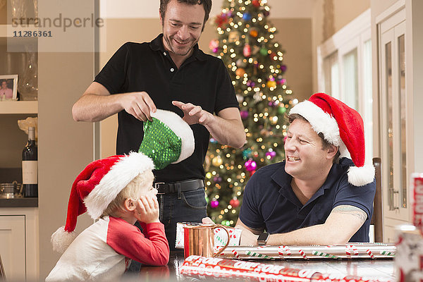 Kaukasische Väter und Söhne mit Weihnachtsmannmützen