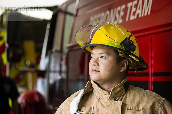 Chinesischer Feuerwehrmann neben Feuerwehrauto stehend