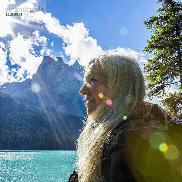 Sonnenstrahlen auf dem Gesicht einer kaukasischen Frau am Bergsee