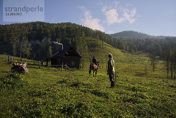 Kaukasisches Mädchen beobachtet Mädchen reitet Pferd