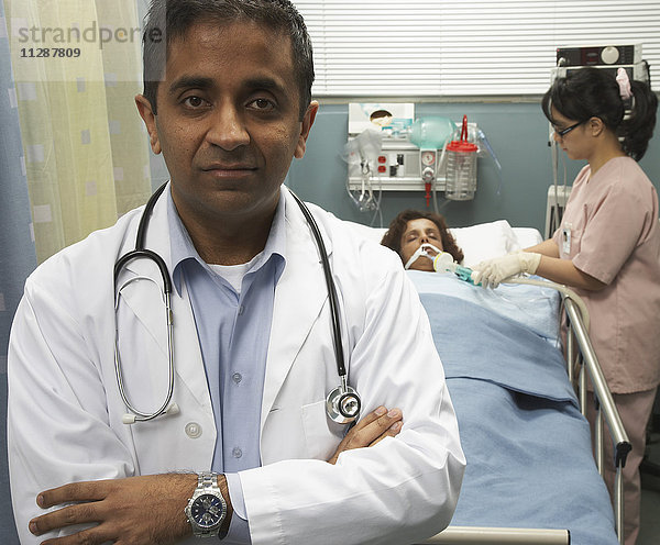 Porträt eines Arztes und einer Krankenschwester  die sich um den Patienten im Hintergrund kümmert