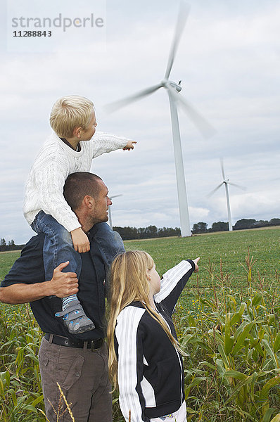 Vater und Kinder mit Blick auf Windkraftanlagen  Dänemark