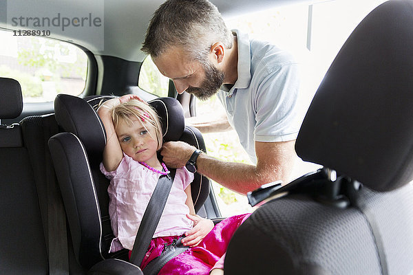 Vater schnallt Mädchen im Auto an