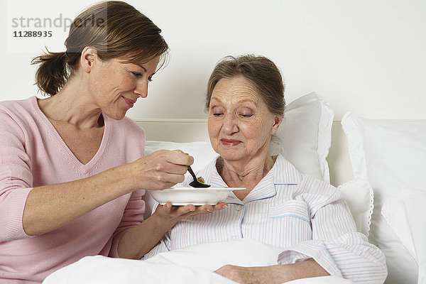 Betreuerin füttert ältere Frau