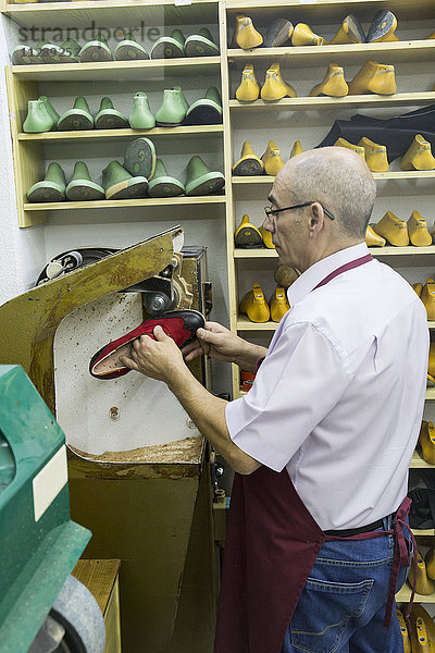 Schuhmacher mit einer Maschine in seiner Werkstatt