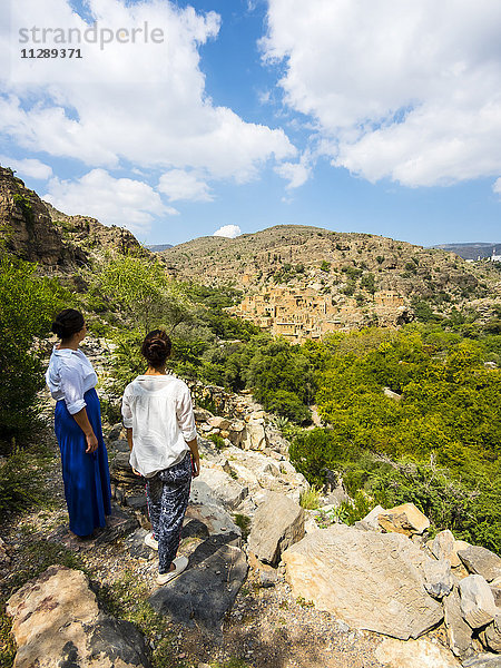 Oman  Jabal Akhdar  Frauen betrachten das verlassene Dorf Wadi Bani Habin