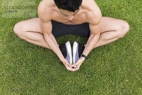 Nackter Athlet im Gras sitzend