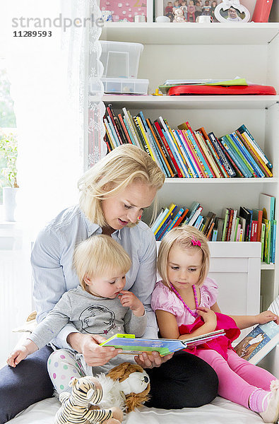 Mutter liest ihren Töchtern ein Buch vor