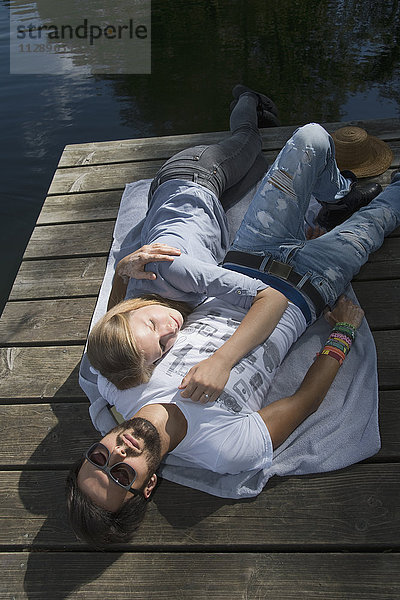 Entspanntes junges Paar auf einem Steg am See liegend