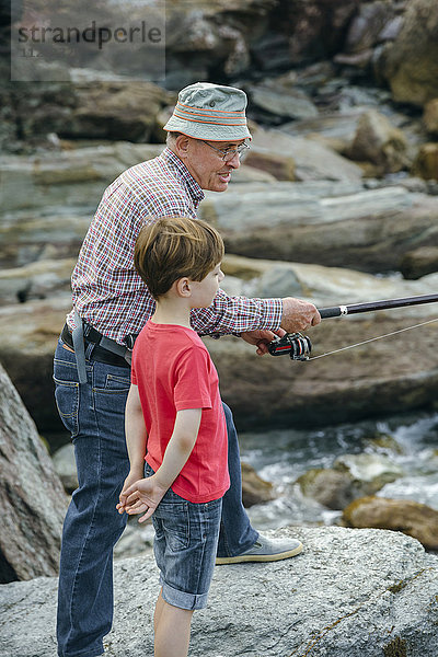 Großvater und Enkel beim gemeinsamen Fischen an der Felsenküste