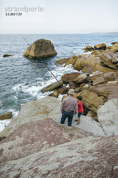 Großvater und Enkel beim gemeinsamen Fischen am Meer