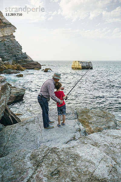 Großvater und Enkel beim gemeinsamen Fischen am Meer