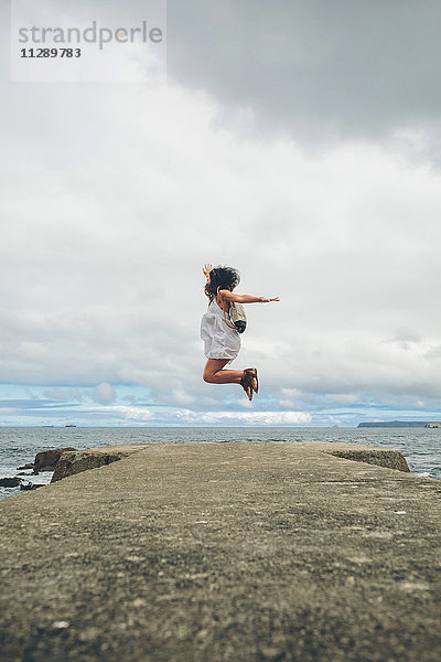 Frau auf dem Pier springt in die Luft