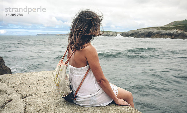 Frau mit Rucksack am Pier mit Blick aufs Meer