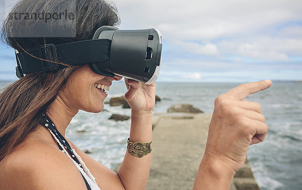 Lächelnde Frau mit Virtual Reality Brille im Freien