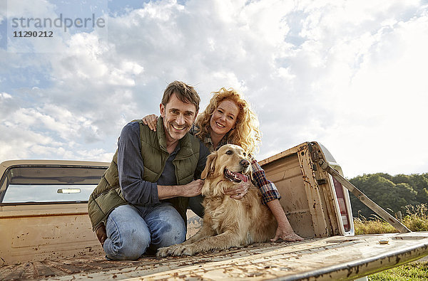 Glückliches Paar mit Hund auf Pick-Up Truck