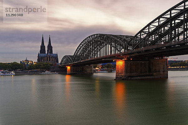 Deutschland  Köln  Blick auf den Kölner Dom mit Hohenzollernbrücke im Vordergrund bei Abenddämmerung