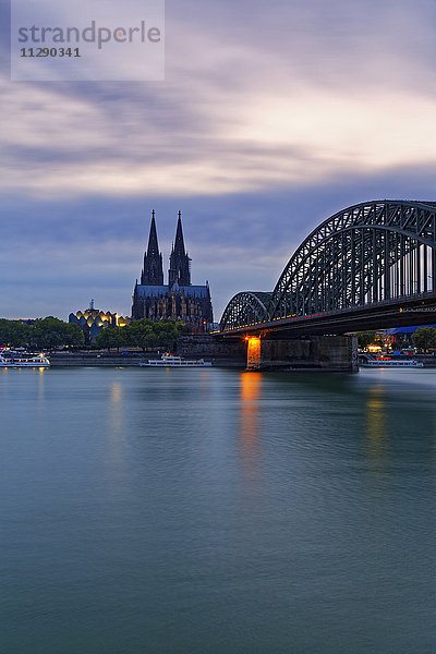 Deutschland  Köln  Blick auf den Kölner Dom mit Hohenzollernbrücke im Vordergrund bei Abenddämmerung