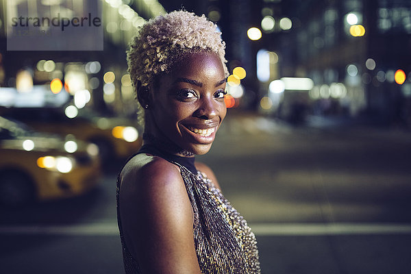 USA  New York City  Porträt der glücklichen jungen Frau am Times Square bei Nacht
