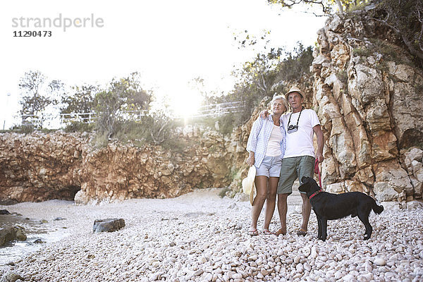 Glückliches Seniorenpaar mit Hund am Strand
