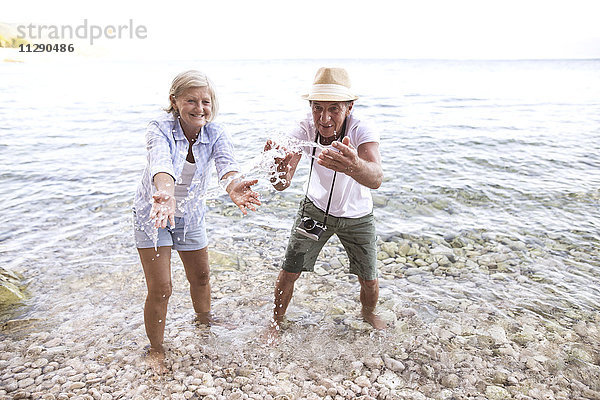 Seniorenpaar  das mit Wasser an der Strandpromenade plätschert.