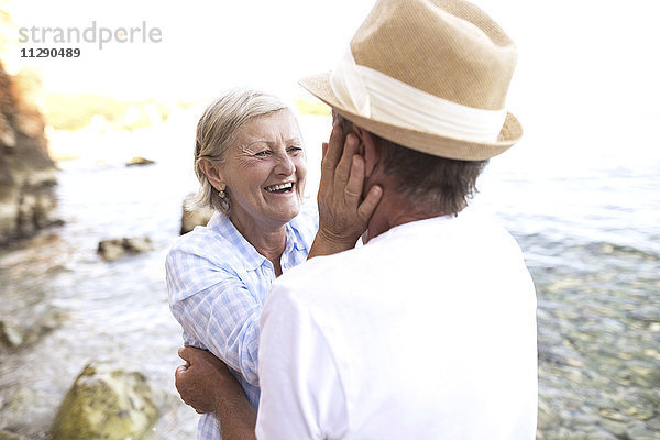 Lachende Frau von Angesicht zu Angesicht mit ihrem Mann vor dem Meer.