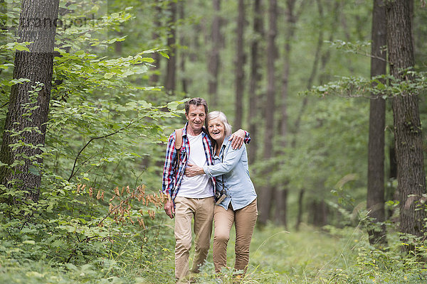 Ein glückliches älteres Paar  das im Wald spazieren geht.
