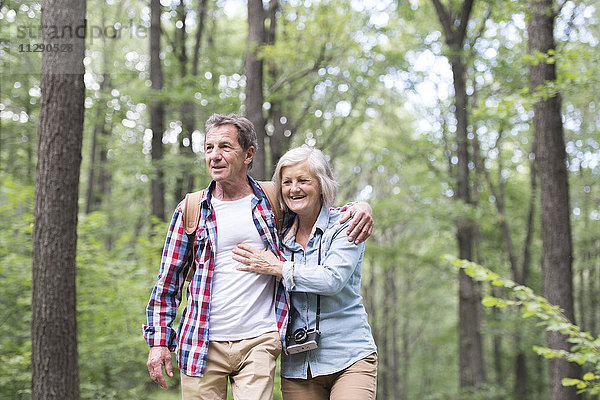 Glückliches älteres Paar  das Arm in Arm im Wald geht.