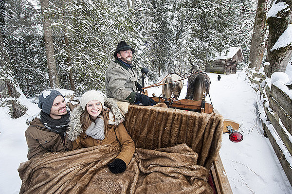 Paar genießt eine Fahrt im Pferdeschlitten im Winter