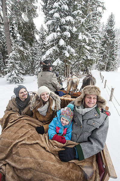 Familie genießt im Winter eine Fahrt mit dem Pferdeschlitten