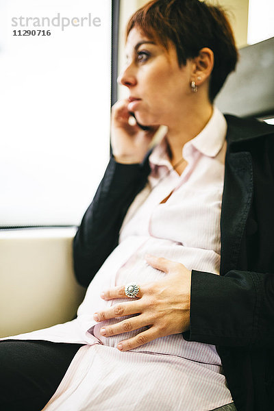 Schwangere Frau im Zug auf dem Handy