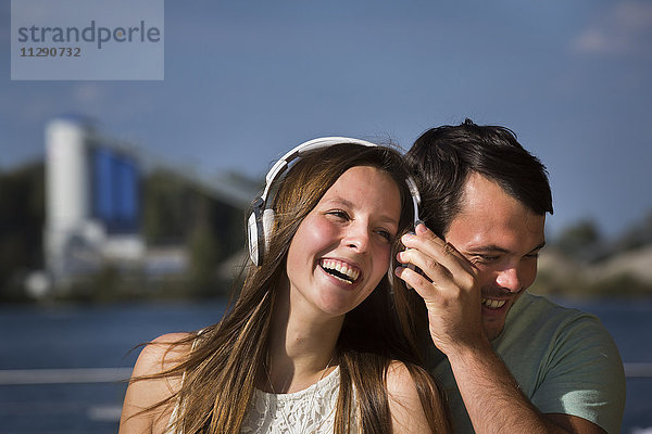 Glückliches junges Paar  das sich Kopfhörer teilt