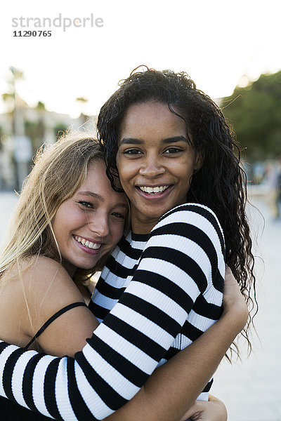 Zwei glückliche junge Frauen  die sich im Freien umarmen.