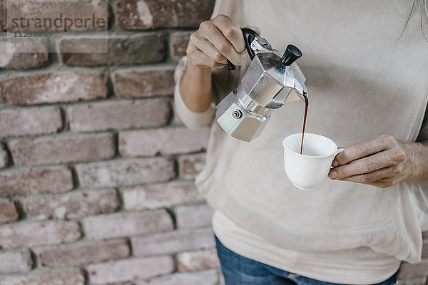 Frau gießt Kaffee in die Tasse