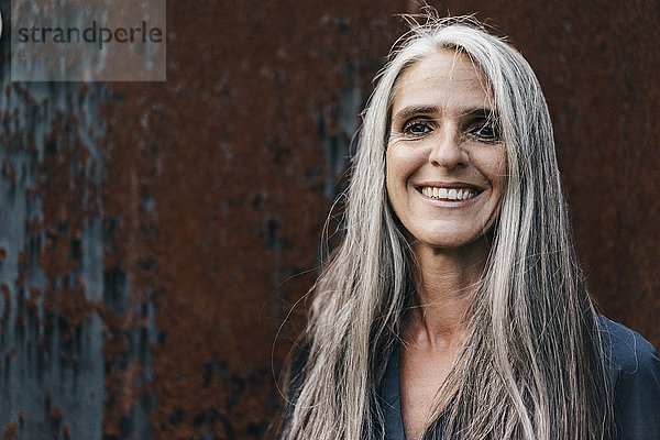 Porträt einer lächelnden Frau mit langen grauen Haaren