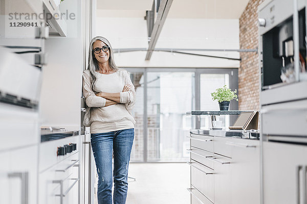 Lächelnde Frau mit langen grauen Haaren in der Küche